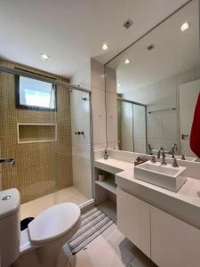 ein Badezimmer mit Toilette, Waschbecken und Spiegel in der Unterkunft Loft Condado Sahy - Mangaratiba in Mangaratiba