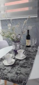 una mesa con dos tazas y una botella de vino en Cozzy apartment near the Aiport Podgorica en Podgorica