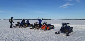 a group of people standing in the snow with their snowmobiles at Lehmonkärki Resort in Asikkala