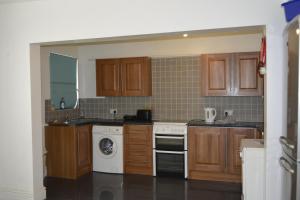 a kitchen with wooden cabinets and a washer and dryer at Kensington Guest House Liverpool in Liverpool