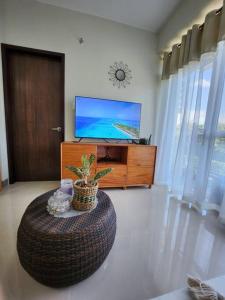 una sala de estar con un reposapiés grande y TV en Aloha Ocean Garden Villas Boracay en Boracay