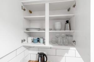 een keuken met witte planken met kopjes en borden bij *NEW* 2 bed apartment on Ber St Norwich in Norwich