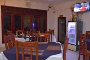a dining room with tables and chairs and a television at Emarald Holiday Homes in Anuradhapura