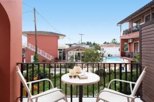 een balkon met een tafel en stoelen en een zwembad bij Marietta's Resort by Konnect, Gouvia Corfu in Gouvia