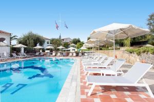 - une piscine avec des chaises longues blanches et des parasols dans l'établissement Marietta's Resort by Konnect, Gouvia Corfu, à Gouviá