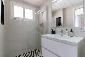 ein weißes Bad mit einem Waschbecken und einer Dusche in der Unterkunft rentafive Nuevo Parking AA Ascensor in Santa Pola