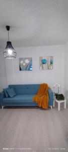 ein Wohnzimmer mit einem blauen Sofa und einigen Gemälden in der Unterkunft PisoYari in Santa Cruz de la Palma