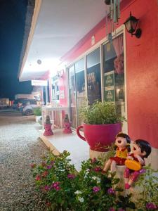 duas bonecas sentadas do lado de fora de um edifício cor-de-rosa em Saan Rak Resort em Prachuap Khiri Khan