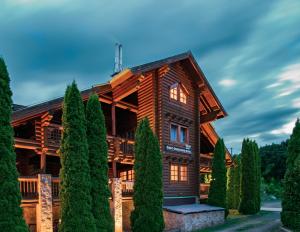 a log home with trees in front of it at Szent Orbán Erdei Wellness Hotel in Kóspallag