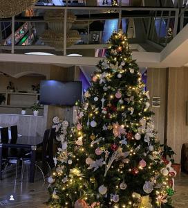 a christmas tree in a room with a table at Hotel Okriba Tbilisi in Tbilisi City
