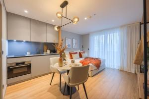 a bedroom with a bed and a table and a kitchen at Icon Apartments by NÔMA in Porto