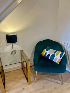 una silla verde con una mesa de cristal y una almohada en KB21 Attractive 2 Bed House, pets/long stays with easy links to London, Brighton and Gatwick en Roffey