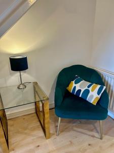 a green chair with a glass table and a pillow at KB21 Attractive 2 Bed House, pets/long stays with easy links to London, Brighton and Gatwick in Roffey