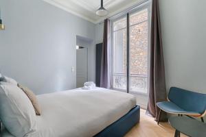 een slaapkamer met een bed, een stoel en een raam bij Champs Elysées Marbeuf Magnifique Appartement 4P in Parijs