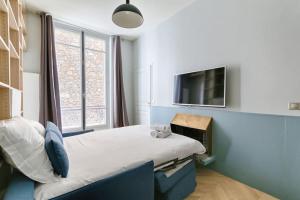 een kleine slaapkamer met een bed en een televisie bij Champs Elysées Marbeuf Magnifique Appartement 4P in Parijs