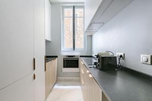 een keuken met witte muren en een zwart aanrecht bij Champs Elysées Marbeuf Magnifique Appartement 4P in Parijs