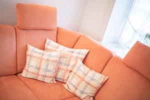 two pillows sitting on an orange couch next to a window at Kleine Kate in Keitum