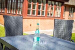 a bottle on a table with glasses on it at Aalernhues in Keitum