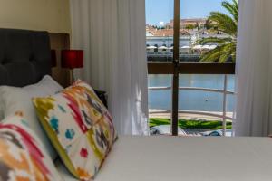 een bed met een raam met uitzicht op een haven bij Princesa do Gilão in Tavira