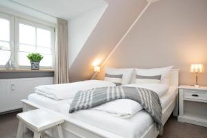 two beds in a room with white walls and windows at Tunghoern Hues Wohnung 07 in Keitum +12 photos