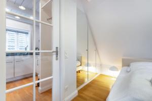 カイトゥムにあるHaus Emilieのベッドと鏡のある白い寝室 +2枚の写真