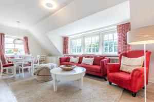 uma sala de estar com mobiliário vermelho e uma mesa em Rotes Kliff em Keitum