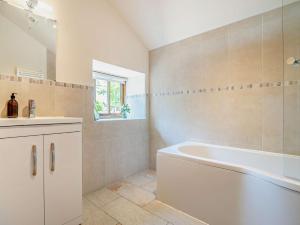 Baño blanco con bañera y lavamanos en 4 Bed in Talgarth BN182, en Talgarth