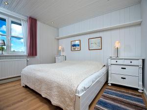 a white bedroom with a bed and a window at Melenbarig Hues in Munkmarsch
