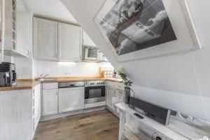 a kitchen with white cabinets and a large painting on the wall at Takerhof Galerie Wohnung 10 in Keitum +10 photos