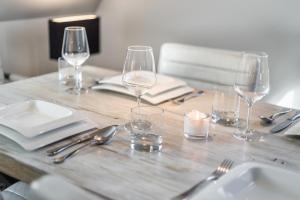 a wooden table with wine glasses and silverware on it at Takerhof Galerie Wohnung 10 in Keitum