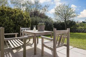 une table en bois avec deux bancs ainsi qu'une table et des chaises dans l'établissement Suederwind 2, à Keitum