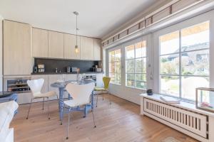 a kitchen with a table and chairs and windows at Lille Hygge in Keitum