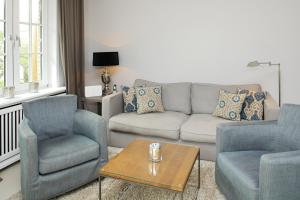 uma sala de estar com um sofá e duas cadeiras e uma mesa em Litz Hues em Keitum