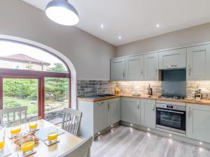 uma cozinha com armários brancos e uma mesa com cadeiras em 2 bed property in Hamsterley 80003 em High Etherley