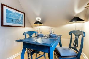 a blue dining room table with two chairs and lamps at Galeriesuite in Archsum