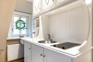 a white kitchen with a sink and a window at Galeriesuite in Archsum