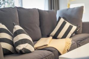 a person sitting on a couch with striped pillows at Uaster Reeg I Parterrewohnung in Archsum