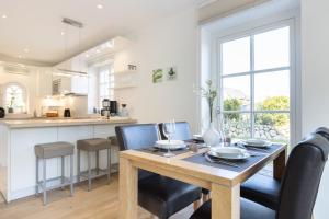 uma cozinha e sala de jantar com uma mesa de madeira e cadeiras em Gode Tiet em Westerland
