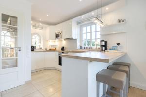 a kitchen with white cabinets and a bar with stools at Gode Tiet in Westerland (Sylt) +19 photos