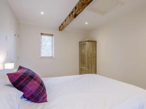 um quarto com uma cama branca e uma almofada roxa em 1 bed in Sherborne 80737 em Wootton Glanville