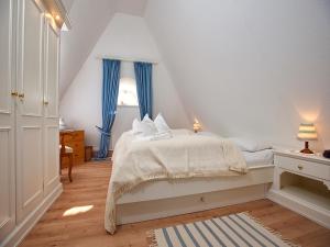una camera da letto con un letto bianco con tende blu di Uaster Reeg II Maisonette ad Archsum
