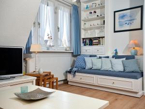 a living room with a blue couch and a tv at Uaster Reeg II Maisonette in Archsum