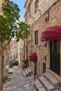 an alley with stone buildings and purple umbrellas at B18 APARTMENT in Dubrovnik