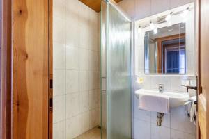 uma casa de banho com um lavatório e um chuveiro com um espelho. em Schwüwong - Apartment 12 em Kelchsau
