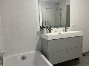 a white bathroom with a sink and a mirror at La Villa Coquette in Vouvray