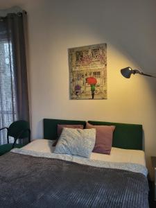 a bed with a green headboard and a painting on the wall at Charmed HomeStay - Zaczarowany in Warsaw
