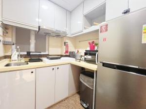 a kitchen with white cabinets and a stainless steel refrigerator at Student Accommodation - 5 Man Cheong Street in Hong Kong
