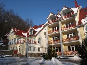 a large white building with red balconies in the snow at Recreation Complex Sunny Resort in Polyana
