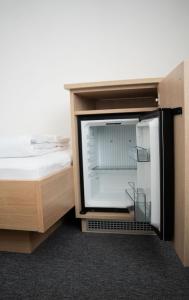 an open refrigerator in a cabinet next to a bed at Frühstückspension Auer - Haus Kargl in Schladming