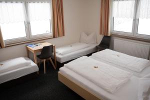 a room with two beds and a desk and windows at Frühstückspension Auer - Haus Kargl in Schladming